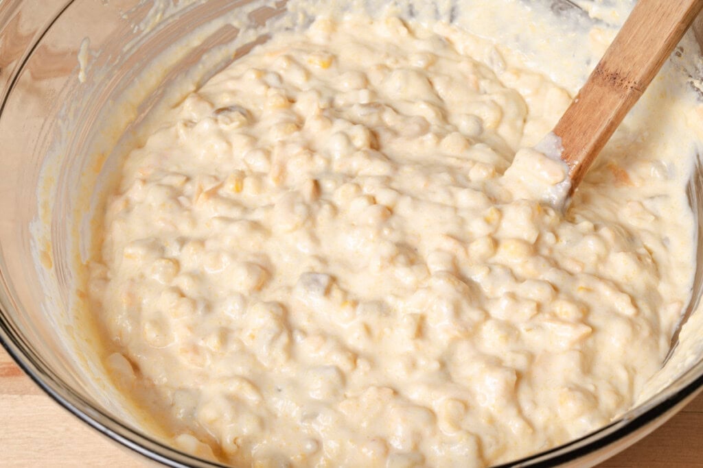 Stirring corn batter with a spoon.