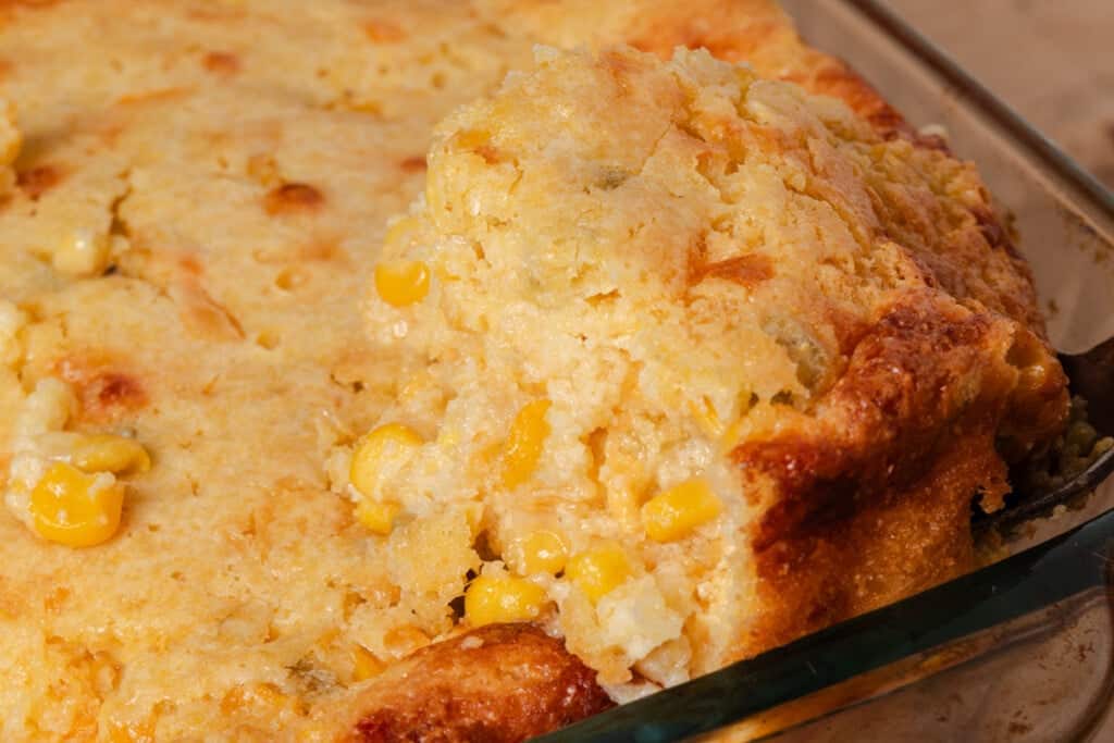 Scooping a serving of cornbread casserole from the dish.