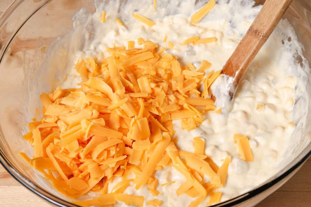 Adding shredded cheese to the wet batter.