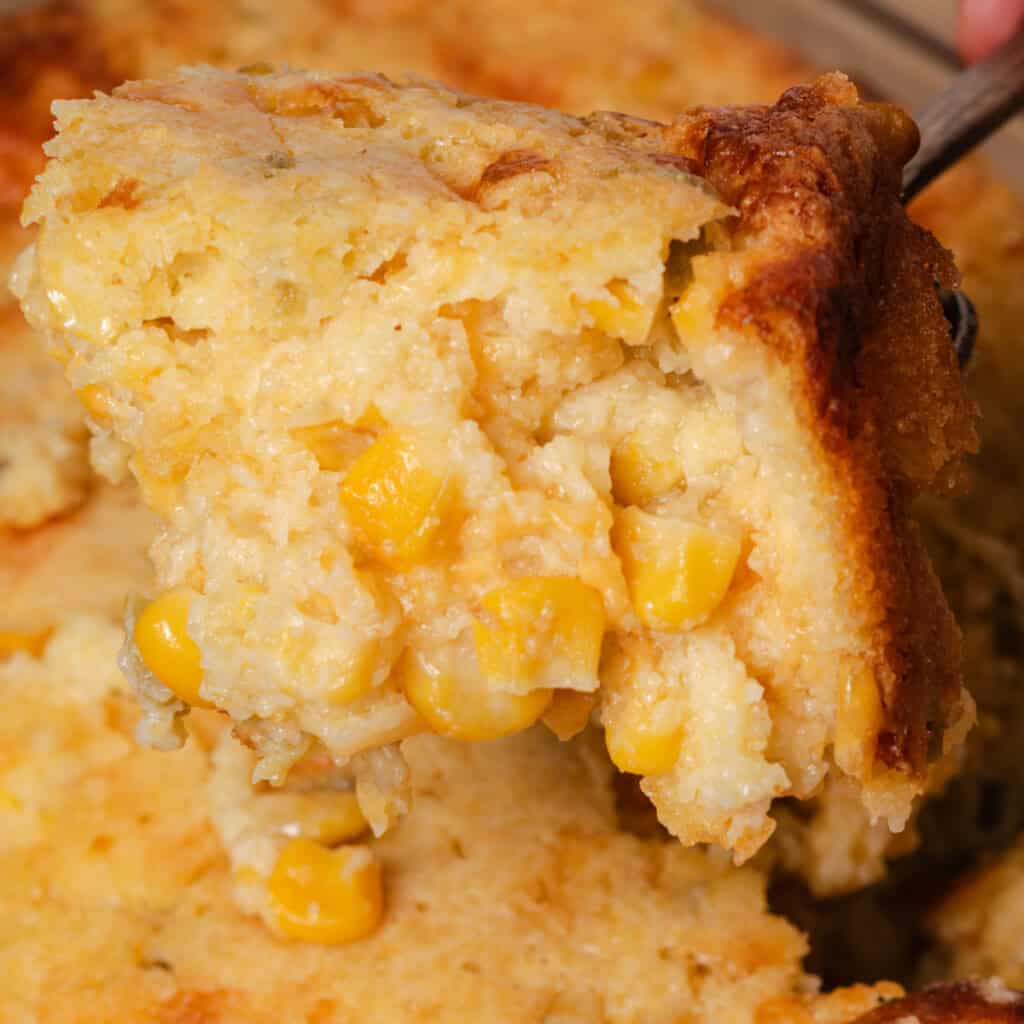 Spooning a serving of cornbread casserole from the dish.