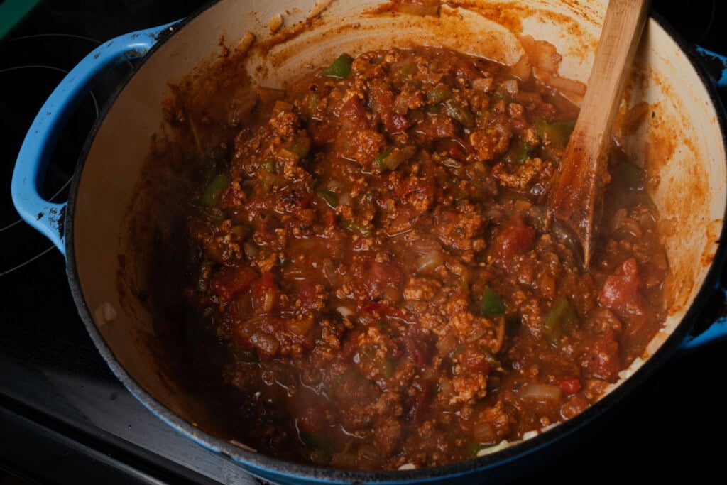 Adding the fire roasted tomatoes and water to pumpkin chili.