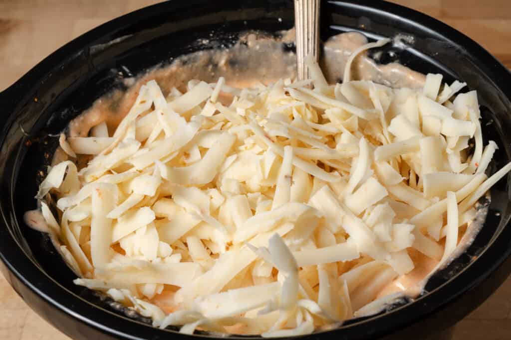 Adding the pepper jack cheese crockpot buffalo chicken dip.