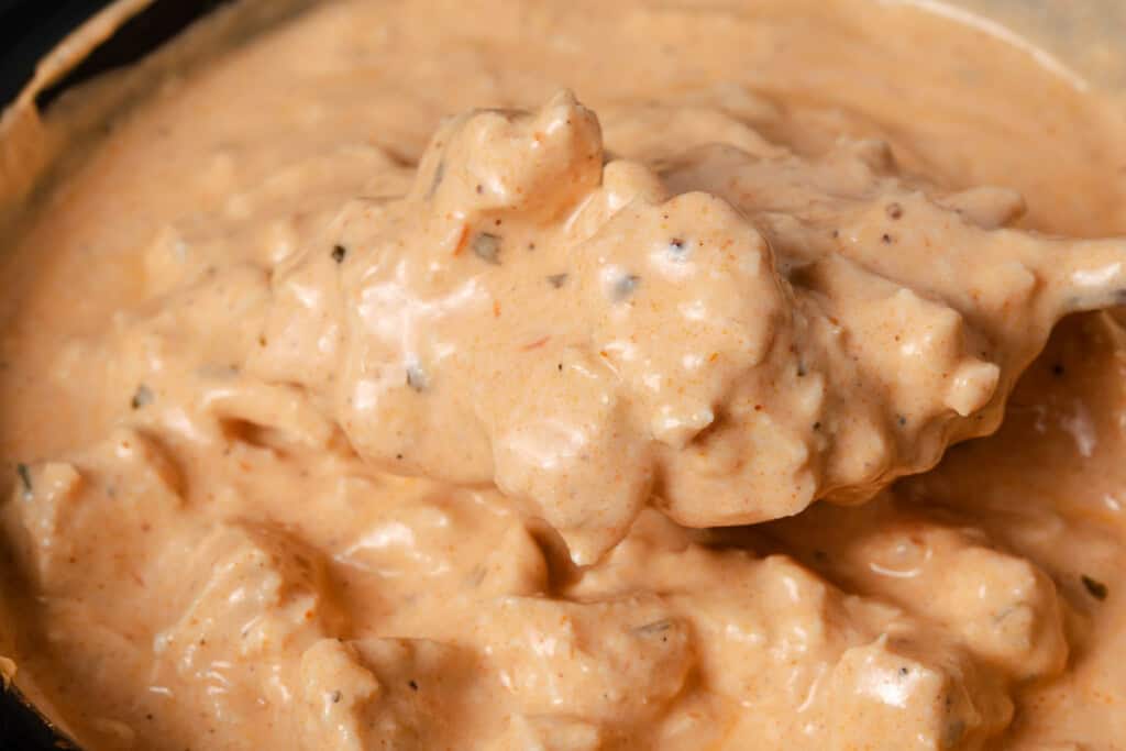Stirring buffalo chicken dip in a crockpot.
