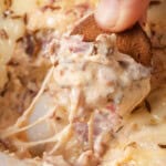 Scooping up homemade hot baked reuben dip on a rye chip.
