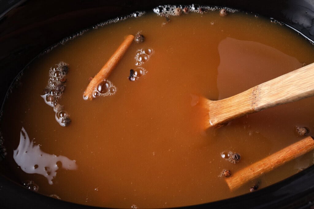 Apple cider, brown sugar, and mulling spices in a slow cooker.