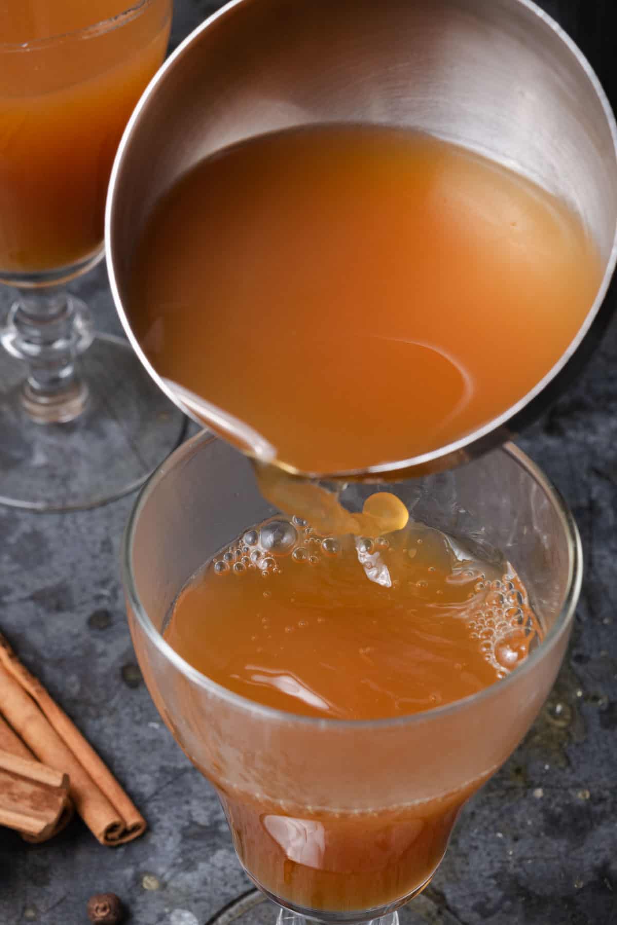Pouring a ladle of hot apple cider into a glass.