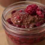 Jars of chocolate chia pudding topped with jammy raspberries.
