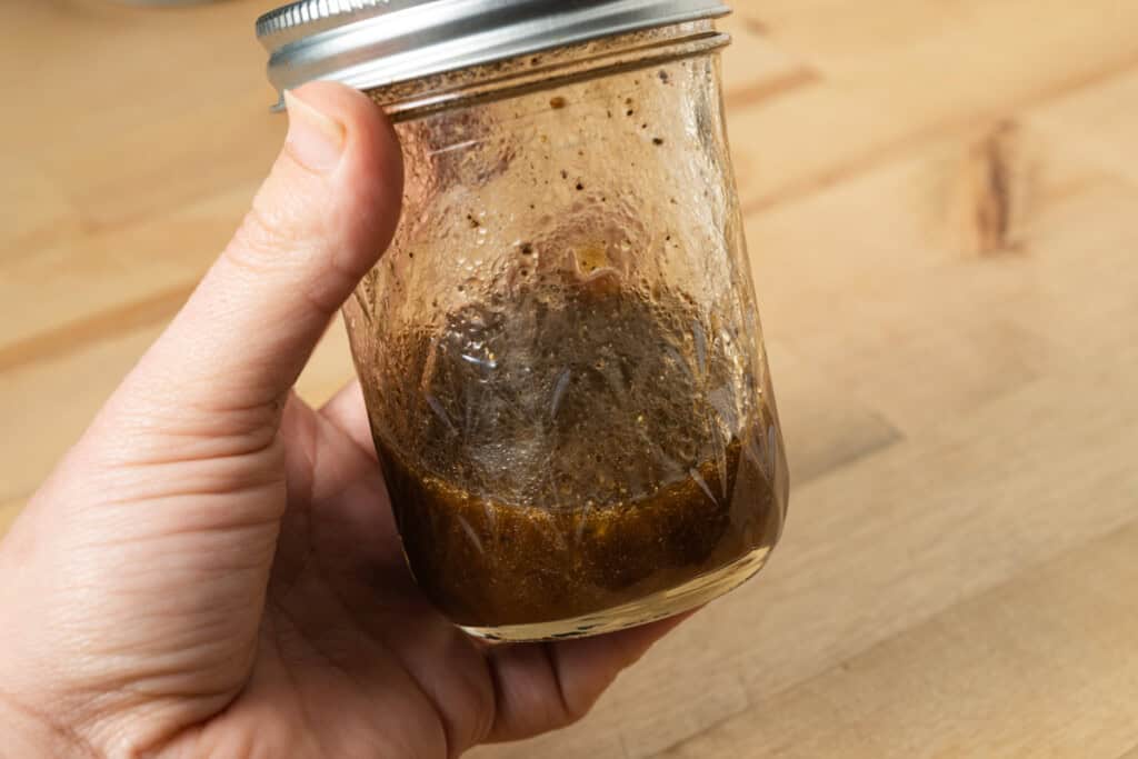 Shaking a jar of homemade balsamic vinaigrette.