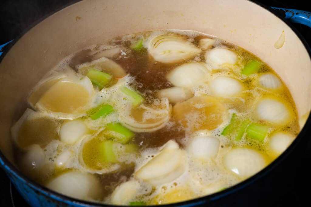 Simmering carrots, onions, celery, and garlic in a pot of homemade chicken stock.