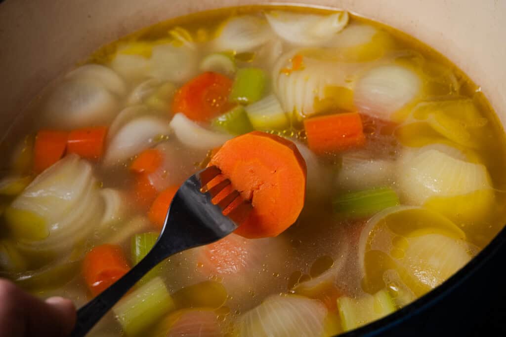 Checking a cooked carrot to see if it's fork-tender.