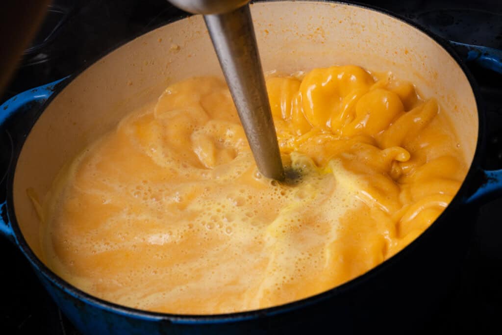 Using an immersion blender to puree veggies in chicken stock.