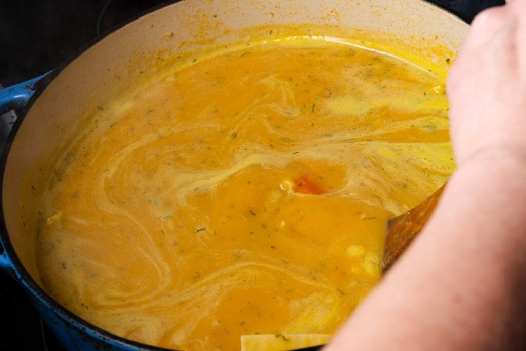 Stirring chicken soup to keep the noodles from sticking.