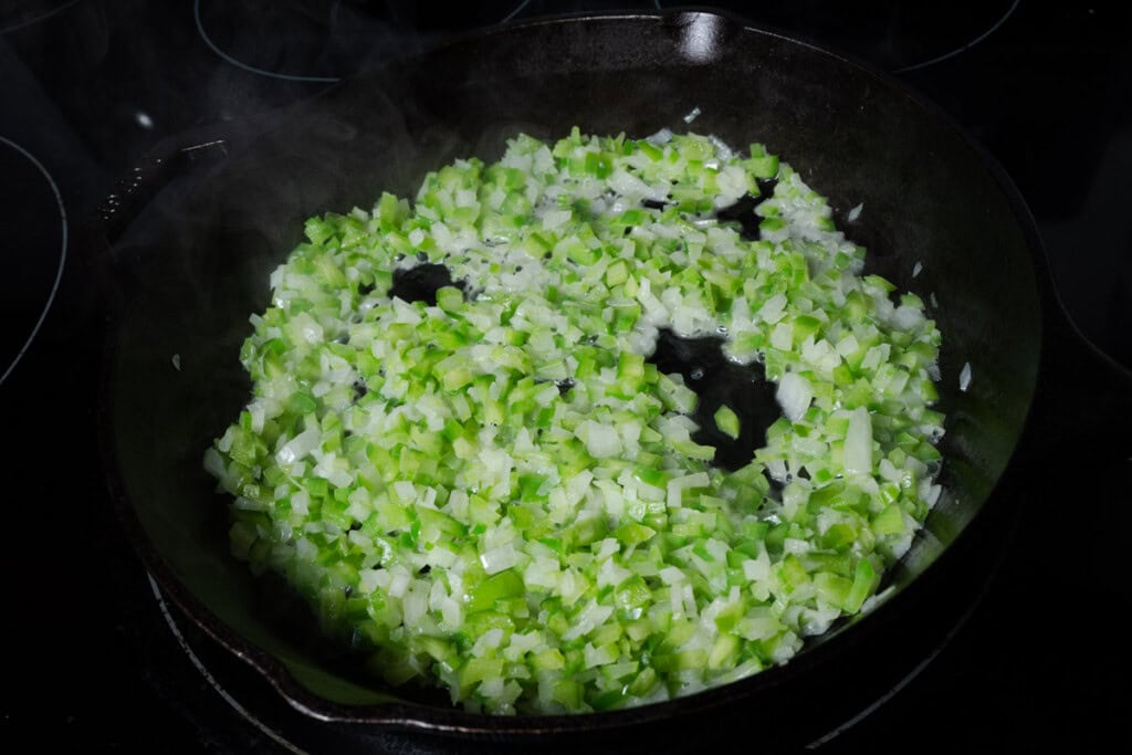 Cooking celery, onions, and bell peppers in butter.