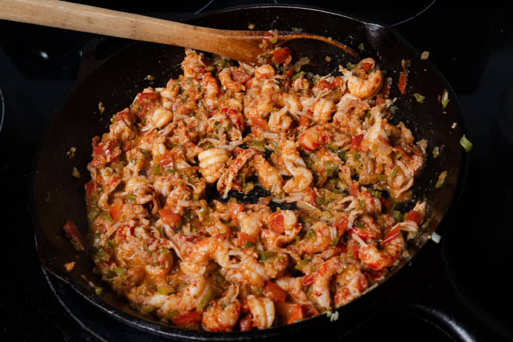 Cooking crawfish tails and creole vegetables in a cast iron skillet.