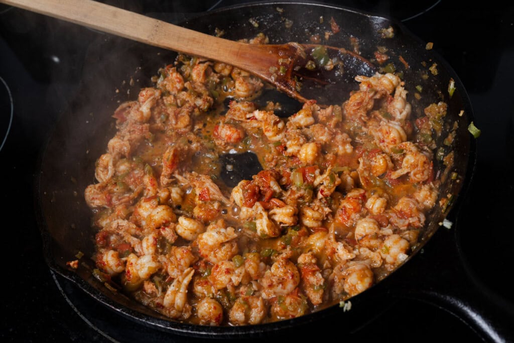 Cooking a creole crawfish mixture in a cast iron skillet.