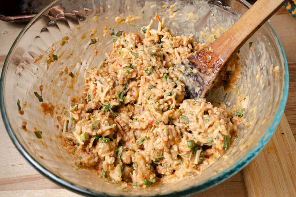 Stirring a bowl of filling for cheesy crawfish bread.