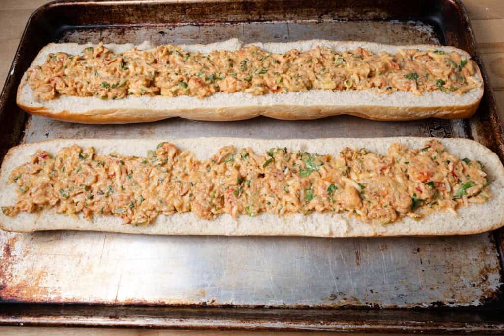 Cheesy crawfish filling spread out on a hollowed out French bread.