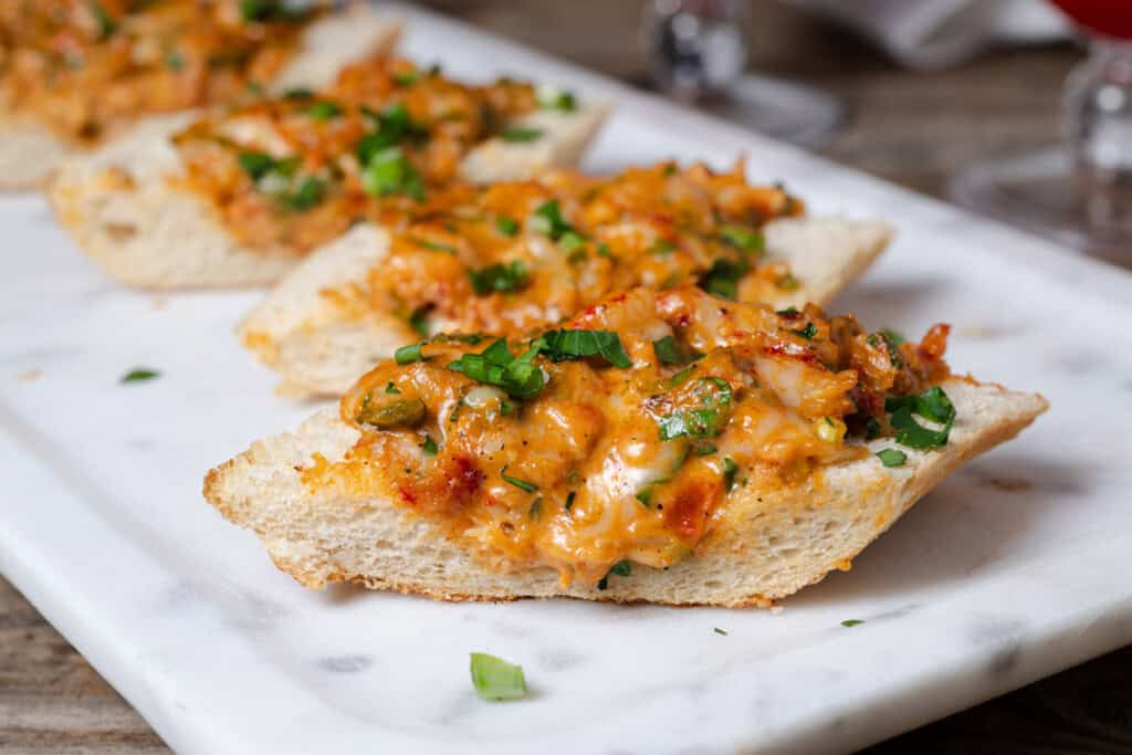 Slices of cheesy New Orleans style crawfish bread on a serving tray.