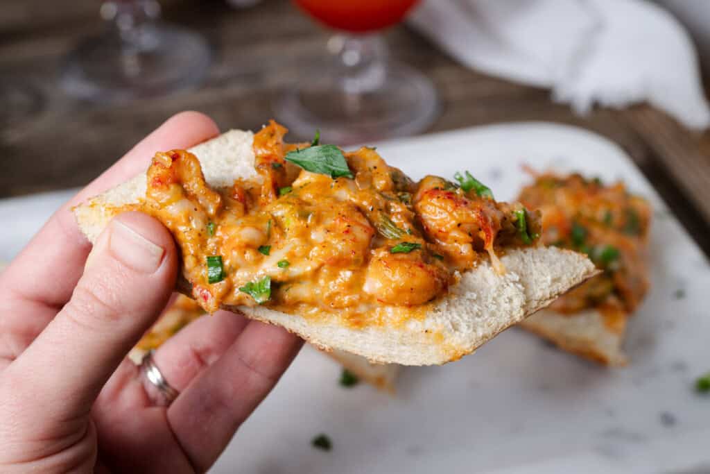A hand holding a slice of crawfish bread.
