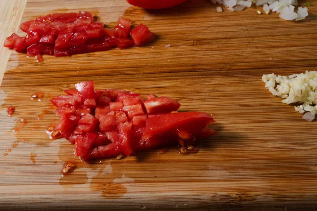 Diced roma tomatoes on a cutting board.
