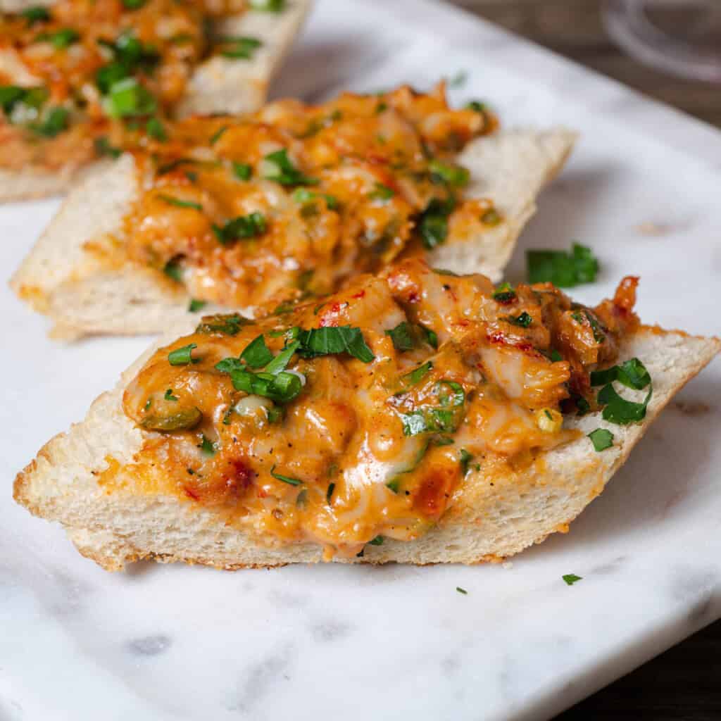 Slices of cheesy New Orleans style crawfish bread on a serving tray.