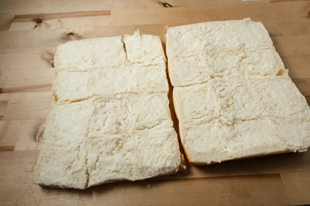 A pack of King's Hawaiian rolls cut in half and spread with garlic butter.