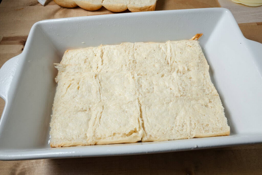 The bottom half of slider buns in a baking dish.
