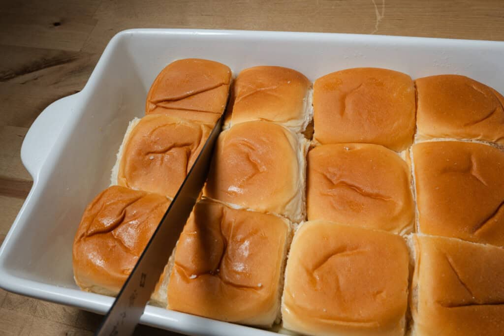 Slicing pizza sliders into individual sandwiches.