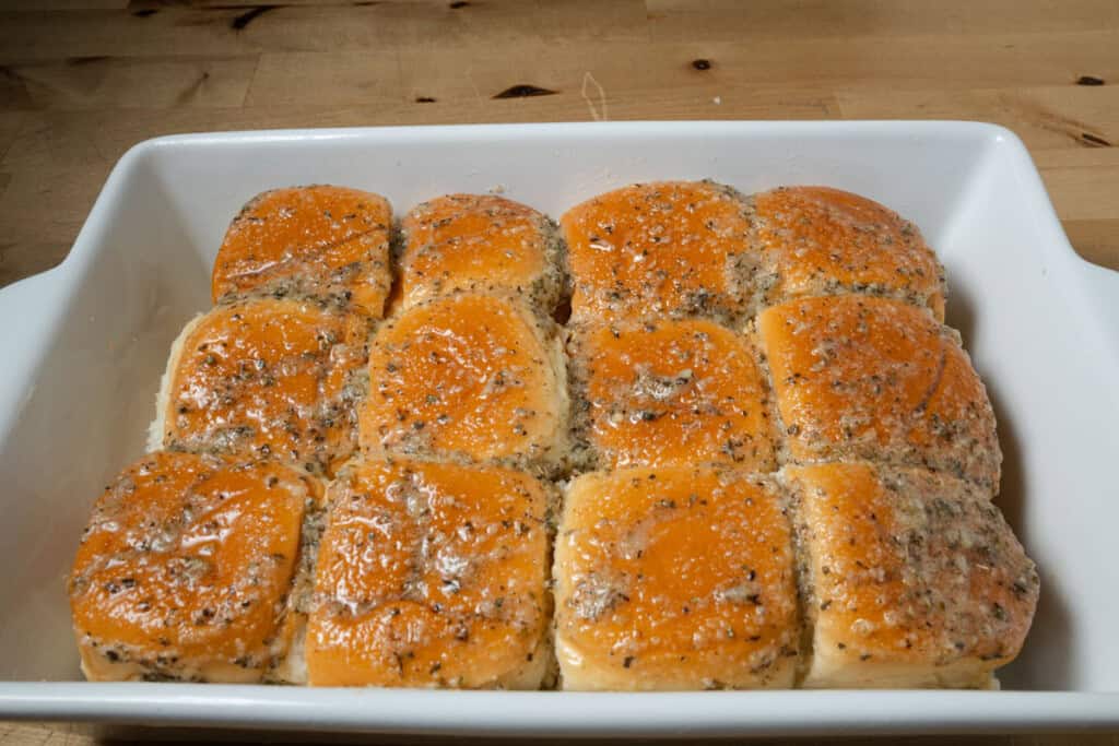 A pan of pizza sliders, brushed with butter topping.