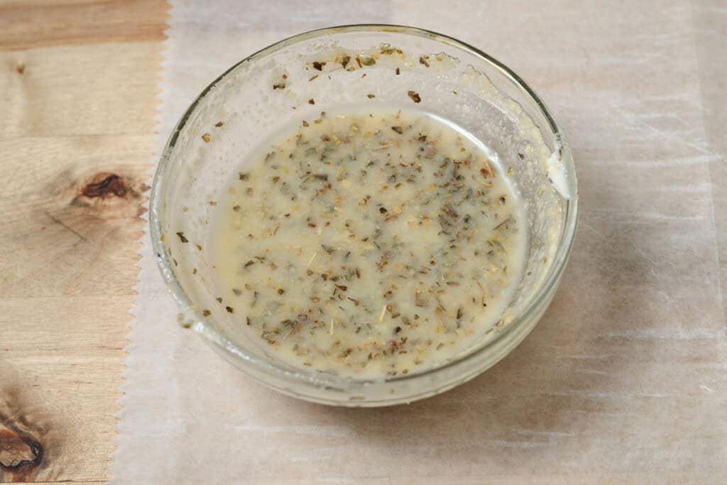 A bowl of melted butter mixed with garlic, parmesan, and herbs.