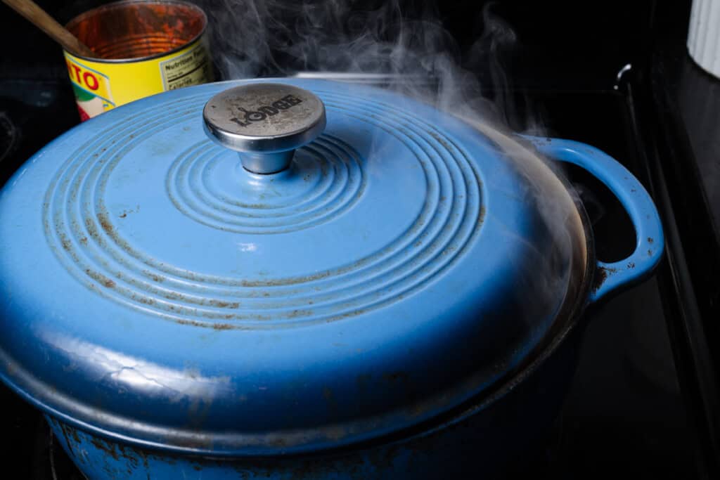 Stuffed pepper soup simmering in a Dutch oven with a tilted lid.