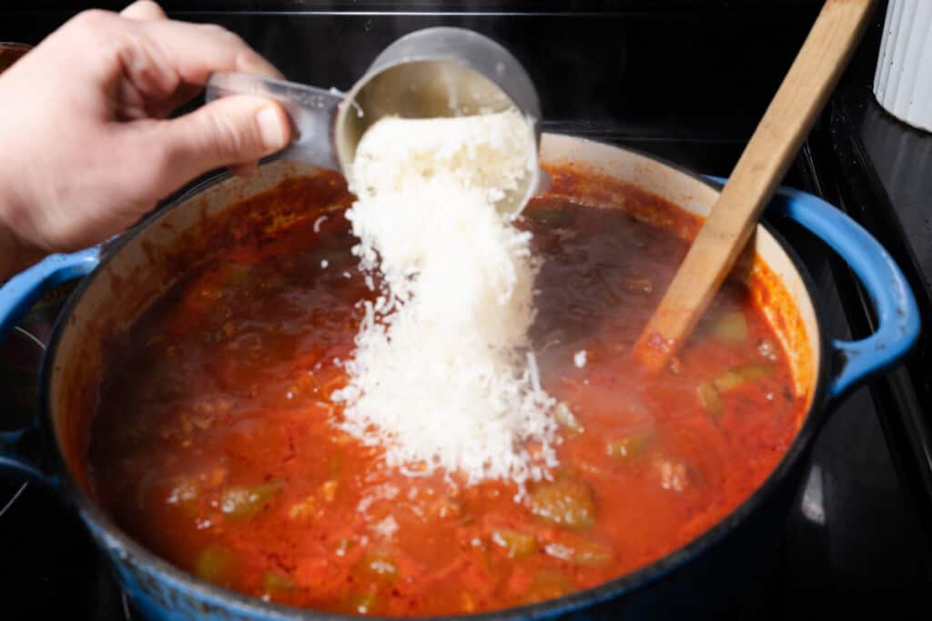 Adding freshly grated parmesan to stuffed pepper soup.