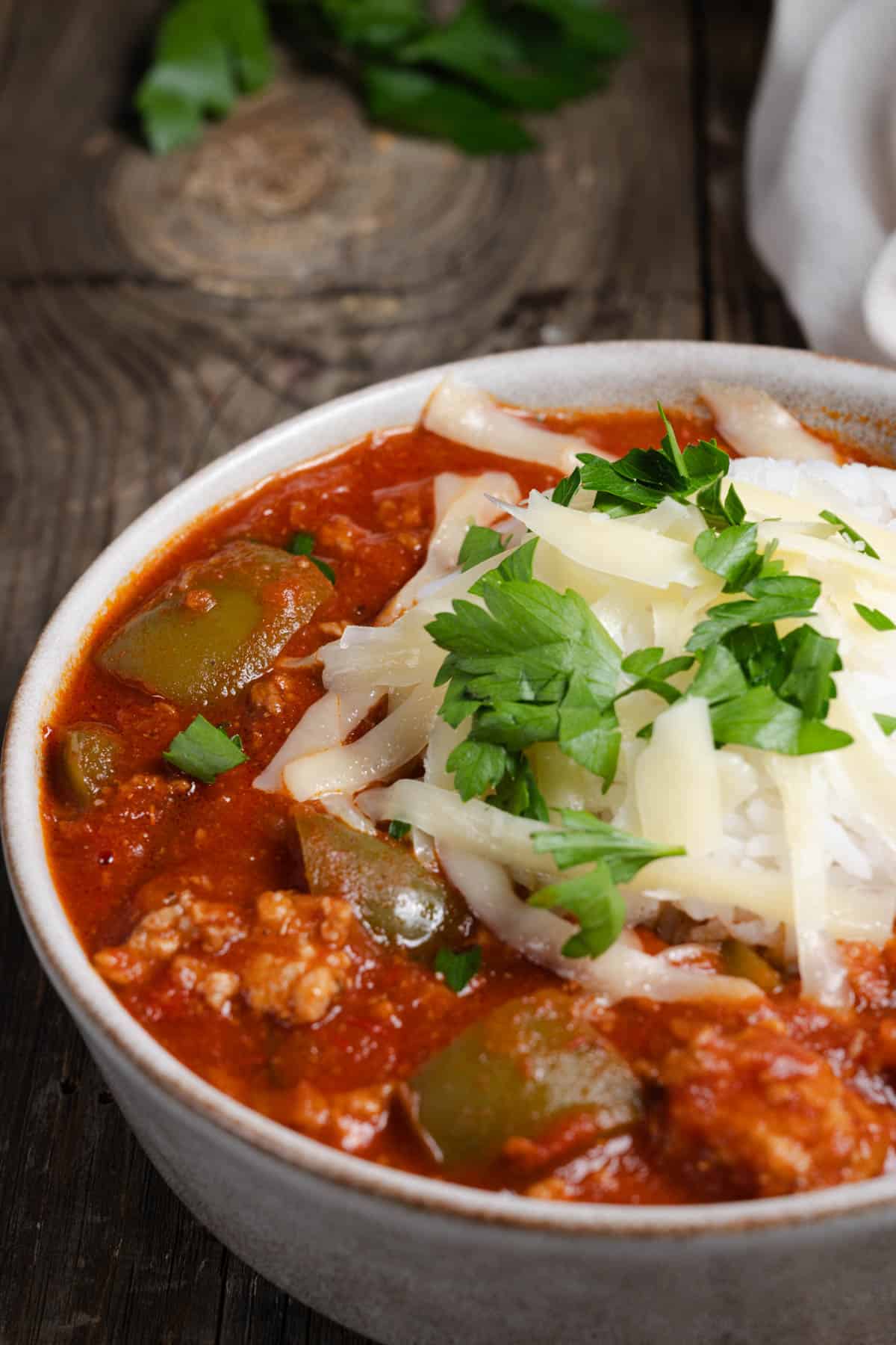 A bowl of stuffed pepper soup with rice, cheese, and parsley.