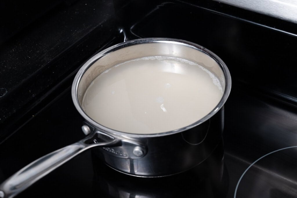 Bringing white rice and water to a boil in a pot.