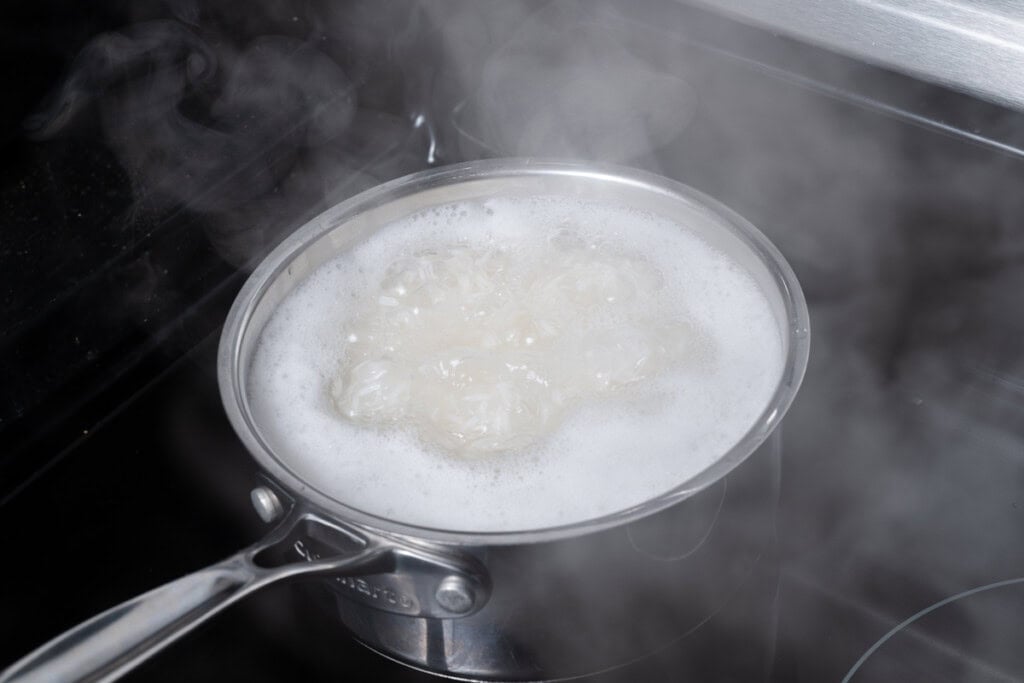 Water and rice reaching a boil in a pot.