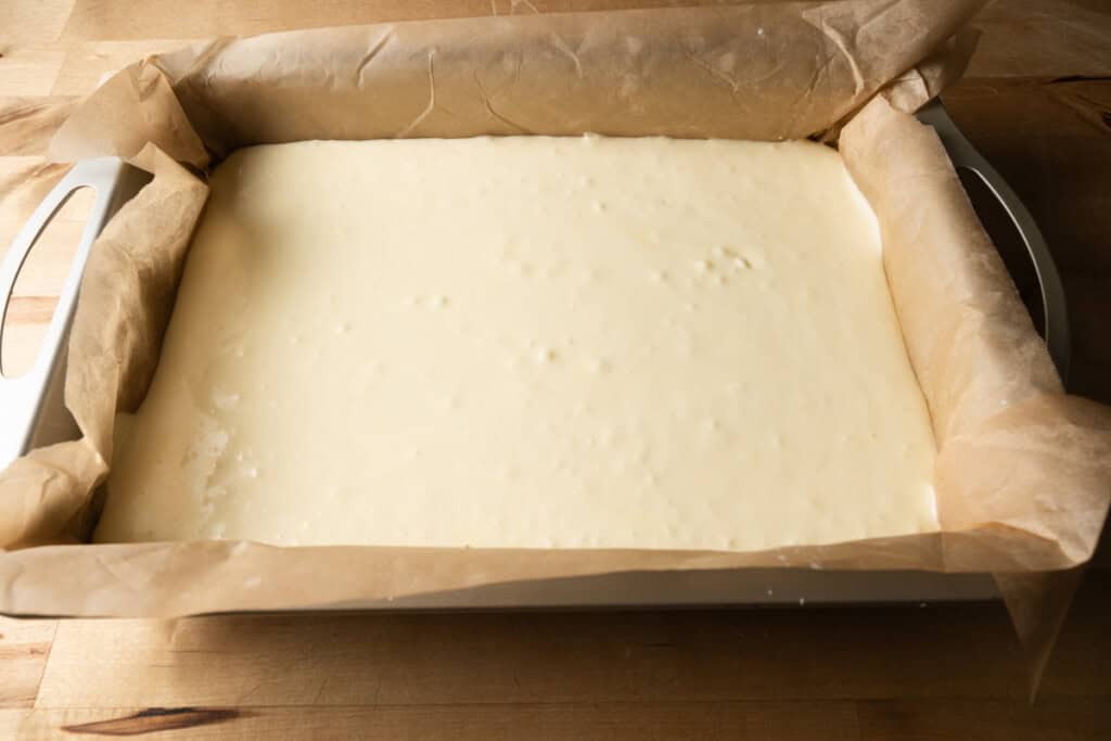 Cream cheese mixture poured over the crust in a cake pan.