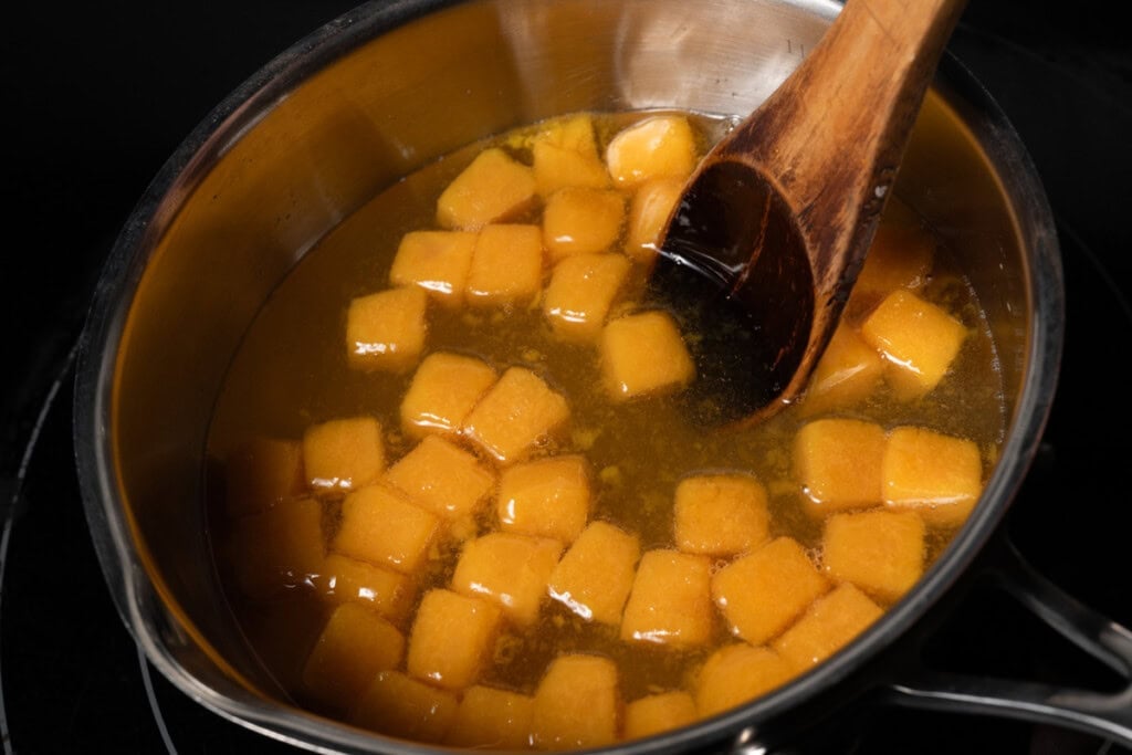 Adding passion fruit puree to a pot of simple syrup.